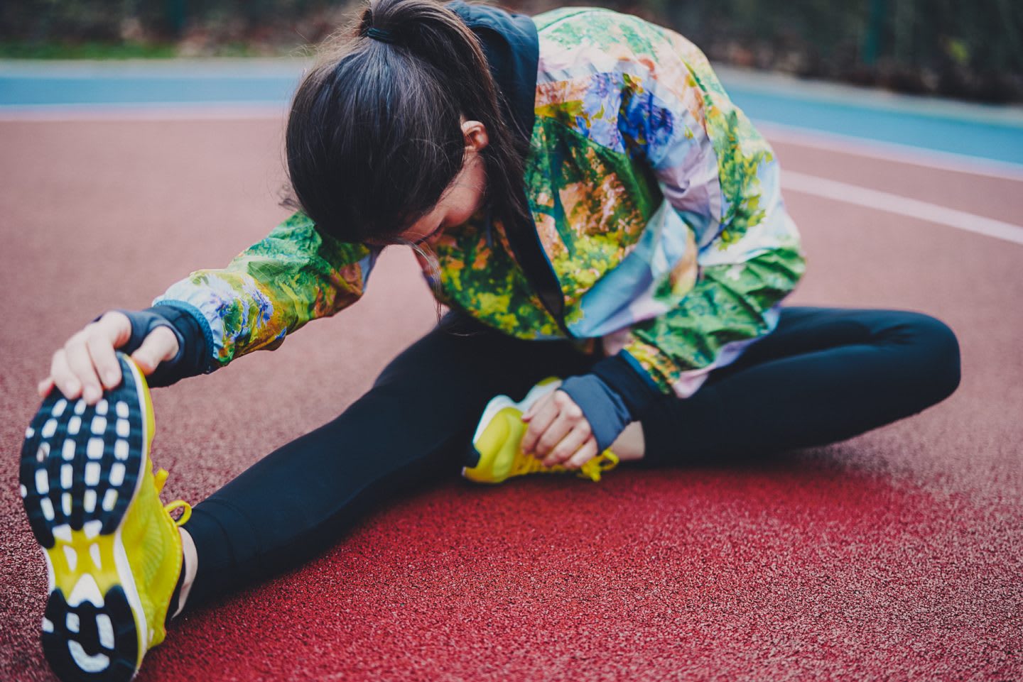 A woman stretches her right leg forward on the ground in preparation for a workout. stretching, preparation, process, routine.