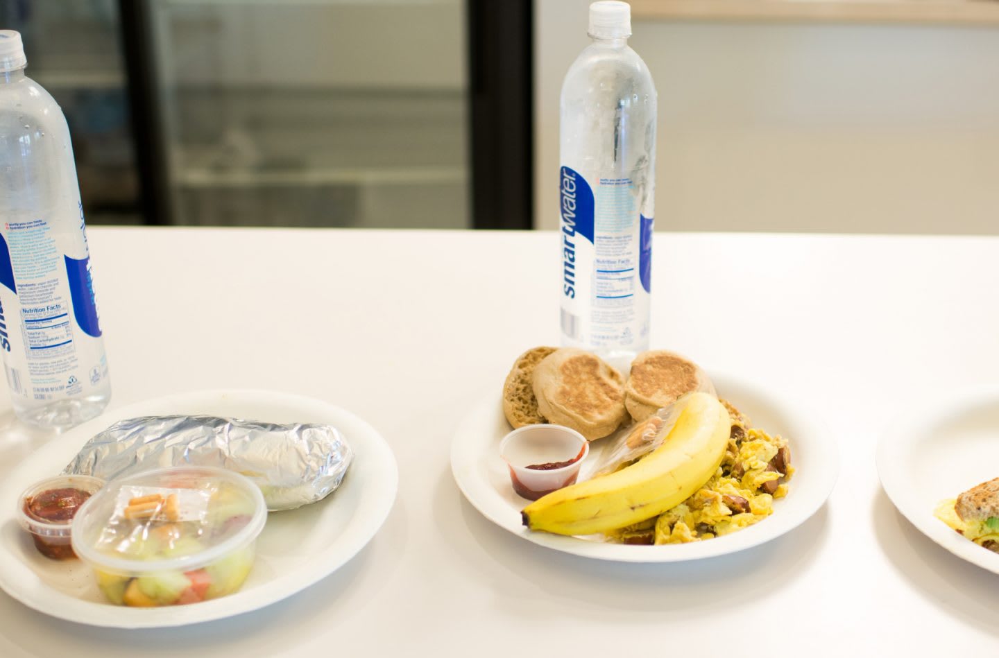 three health meals are set onto a table each with a bottle of water. nutrition, food, healthy snack, water.