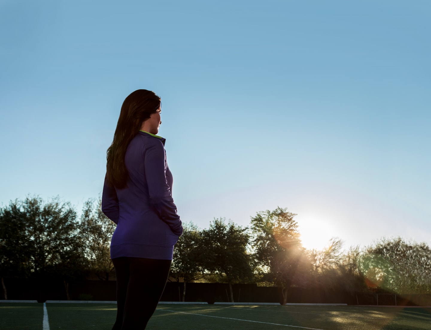 a woman stands in reflection in a field towards the sunset. reflection, peacefulness, sunset, morning