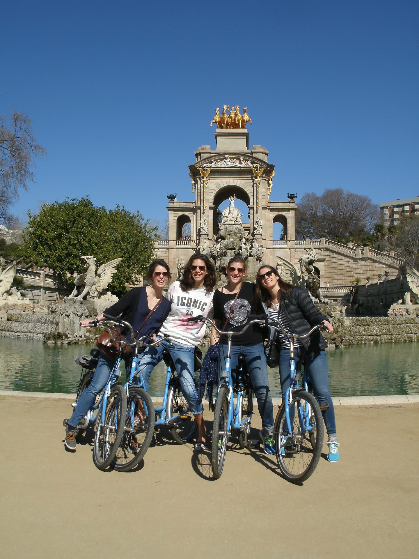 A group of friends sit together on the bicycles in front of a fountain in a park. friendship, bonding, guided tour, outdoors