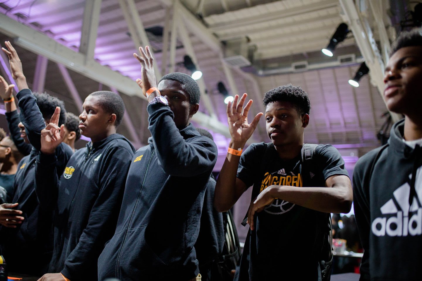 A group of teenagers wait in line holding their hands up to ask a question. curiosity, questions, learning, patience