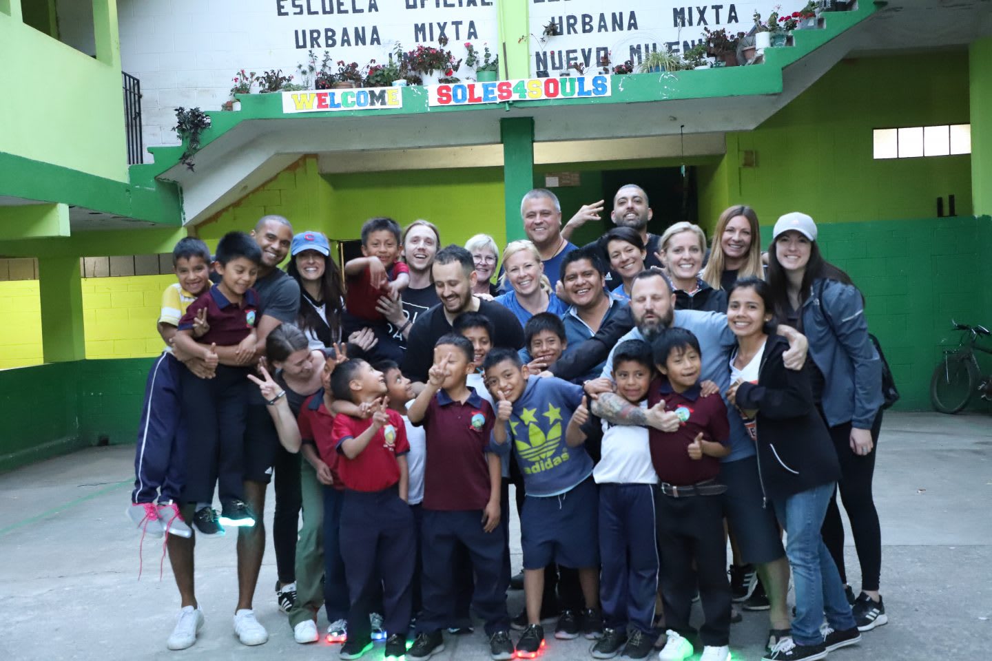 A group of teachers and children stand together to capture a group photo. children, school, happy, teachers, students