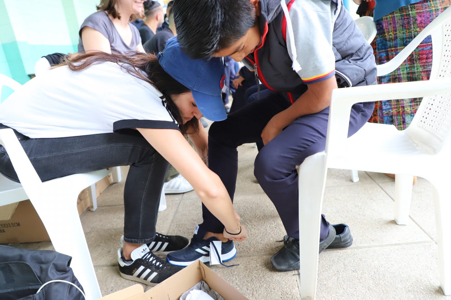A woman bends to help a little girl put on a new pair of shoes. helpful, kindness, sneakers, helping hand