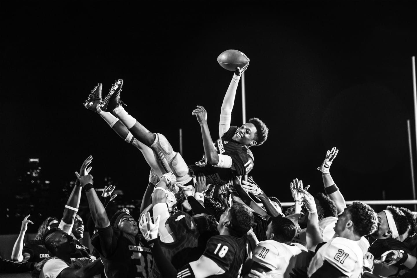 A team of american footballers hold up a team member in celebration of a win. american football, team, teammates, win, celebration
