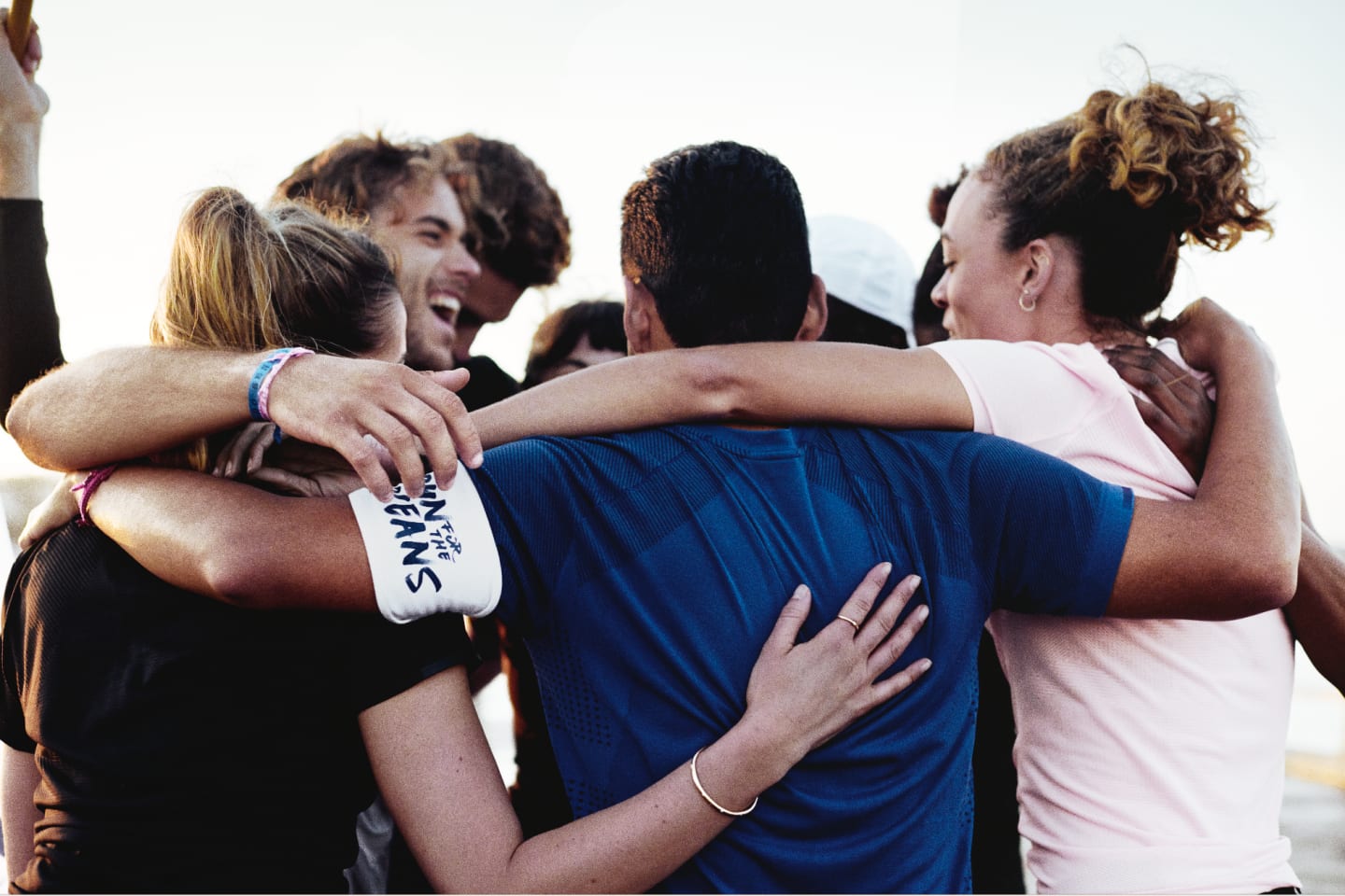 A team come together to form a huddle proud of each others running efforts. run, team, proud, celebration, teamwork, parley, ocean