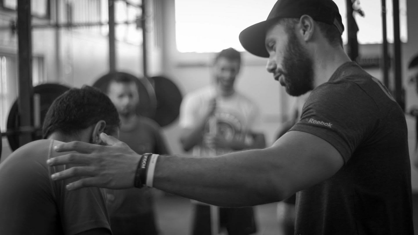 Black and white picture of a fitness coach helping an athlete with the execution of a fitness exercise. injury, adidas, GamePlan A, setback, coach, coaching, motivation, career