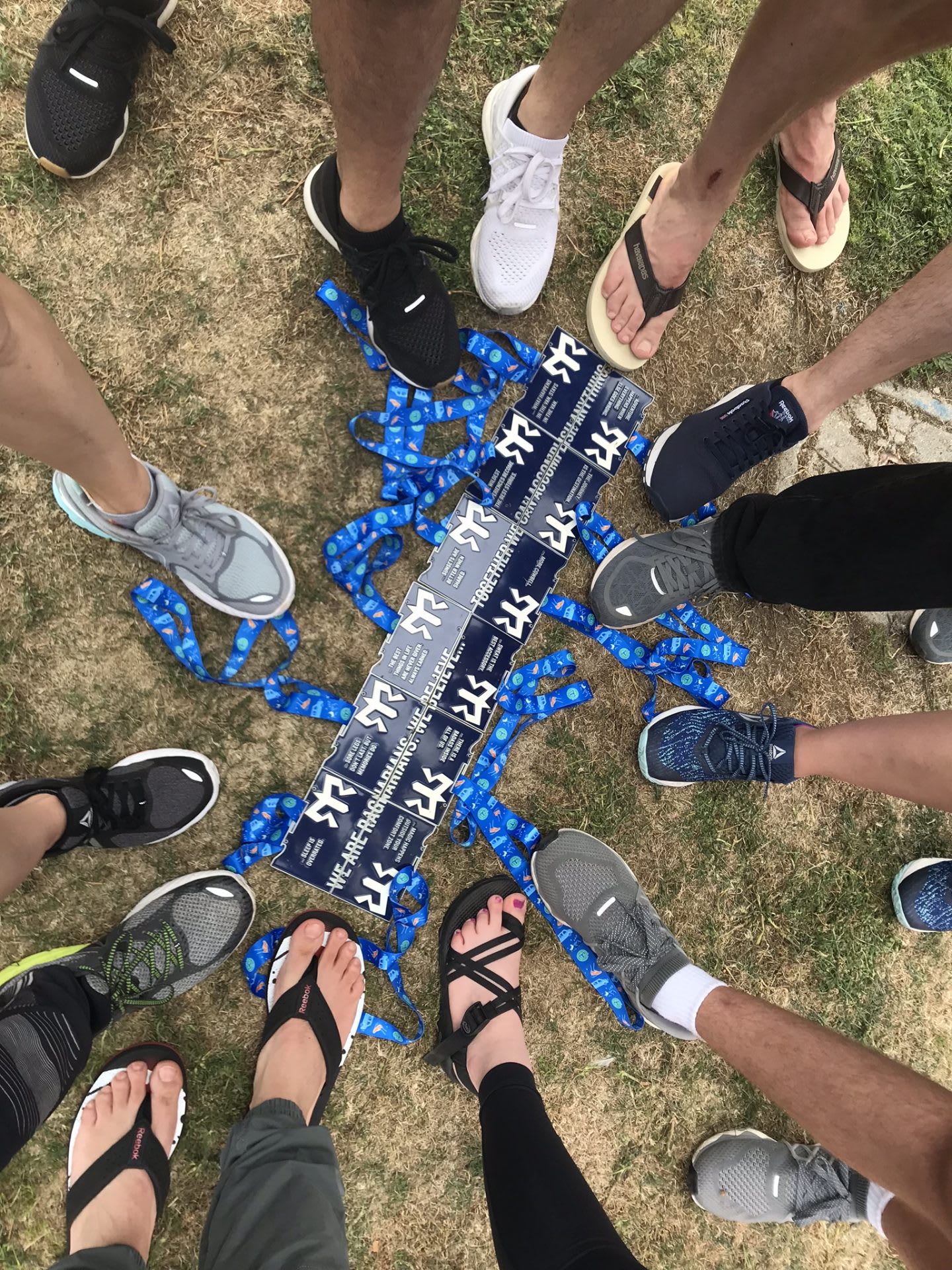 All the runners place their feet beside the relay entry badges. team, support, anticipation, excited, bonding