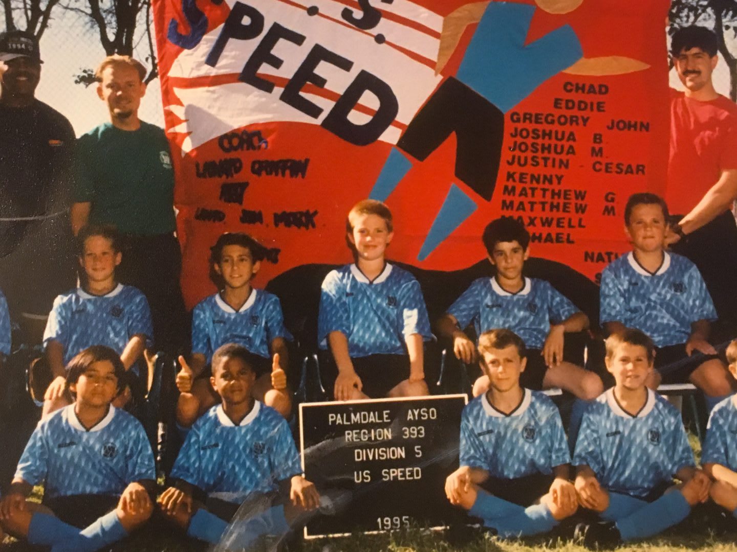 A group of young footballers come together as a team for a photo with their team mates and their coach. football, team, children, coach