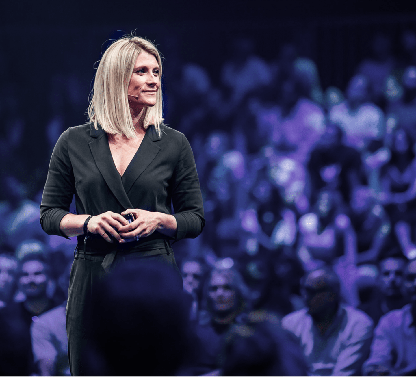 adidas leader Kate Woods standing on stage and smiling with the audience in the back.