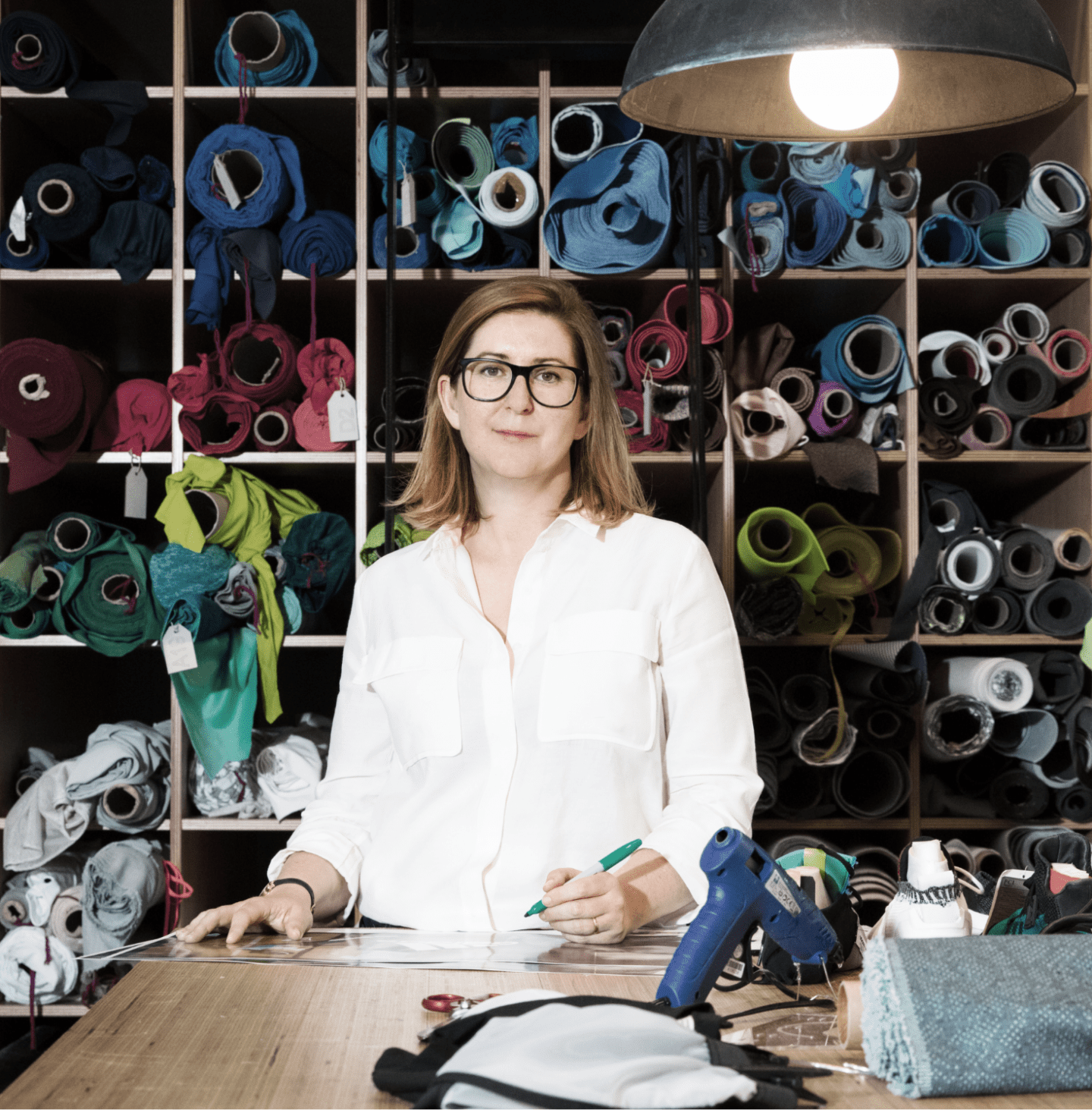 adidas leader Lisann Costello holding a pen and standing at a table in front of a textile material library in a MakerLab environment at adidas.