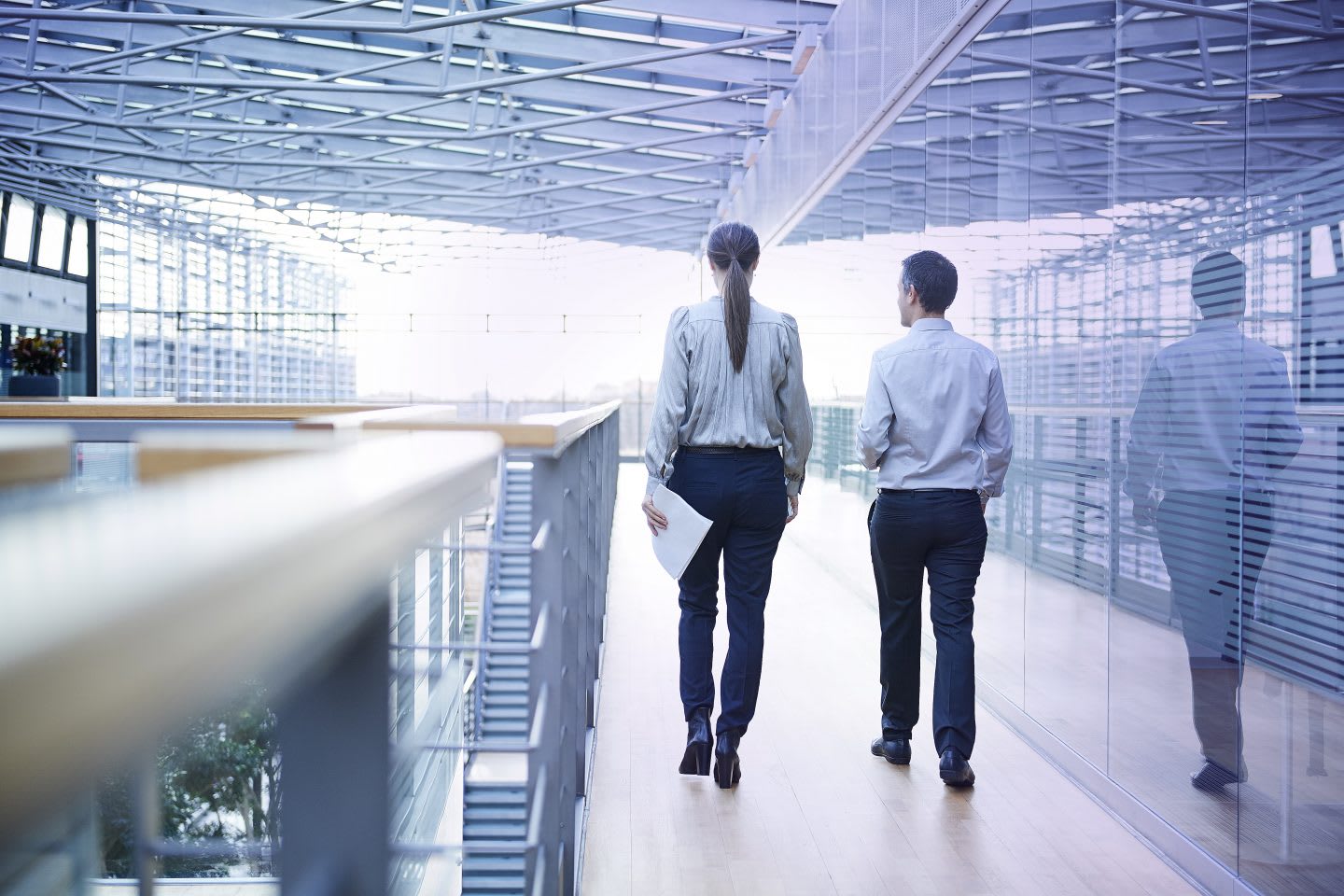 Rear view of businessman and woman walking on office balcony. Mental strength, brainwaves, career, sports, synchronized brains, performance, psychology, research, GamePlan A