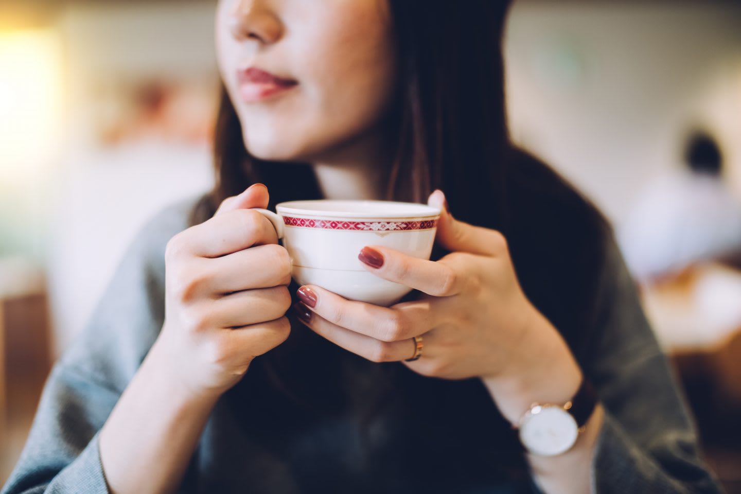 Woman with a watch holding teacup with red nail polish looking out of the window, calm, serene, relax, cafe, thinking, daydream, leisure, inspired, coffee, tea, GamePlan A