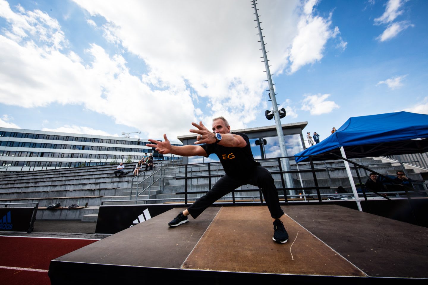 Mark Verstegen doing a lunge on stage while presenting a workout at the adidas Stadium in Herzogenaurach, Germany. EXOS, leadership, leadership skills, leadership advice, workout, fitness, coaching, GamePlan A