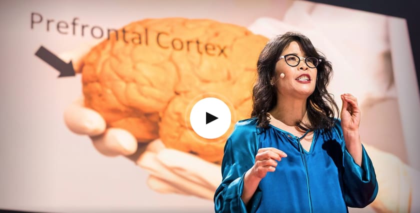 Woman wearing glasses and blue shirt giving a speech on stage in front of picture of brain, TED Talks, headpiece, hand gestures, talk, GamePlan A