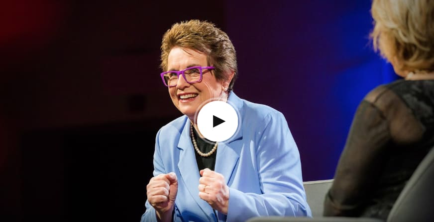 Woman wearing a blue suit and purple glasses smiling while giving talk on stage, Billie Jean King, TED Talks, speaker, talk, inspiration, confidence, challenging status quo, GamePlan A