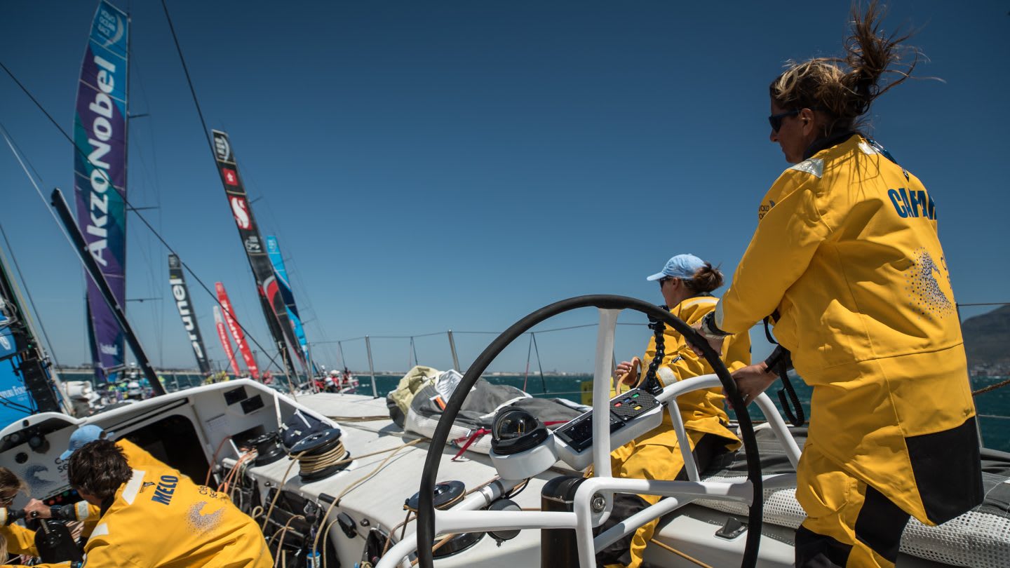 Woman in yellow sailing jacket on yacht during Inport Race in Cape Town, Dee Caffari, sailor, yachtswoman, sailing, steering, confidence, positivity, leadership, GamePlan A