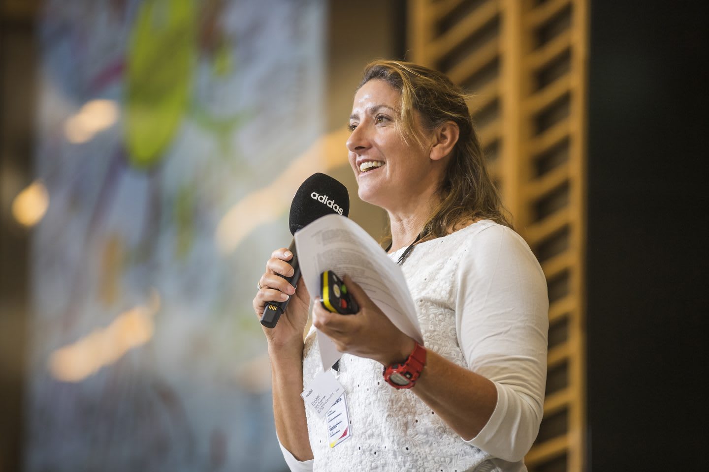 Woman holding adidas microphone smiling and speaking on stage, speech, presentation, Dee Caffari, sailor, yachtswoman, female, sports marketing, adidas, GamePlan A