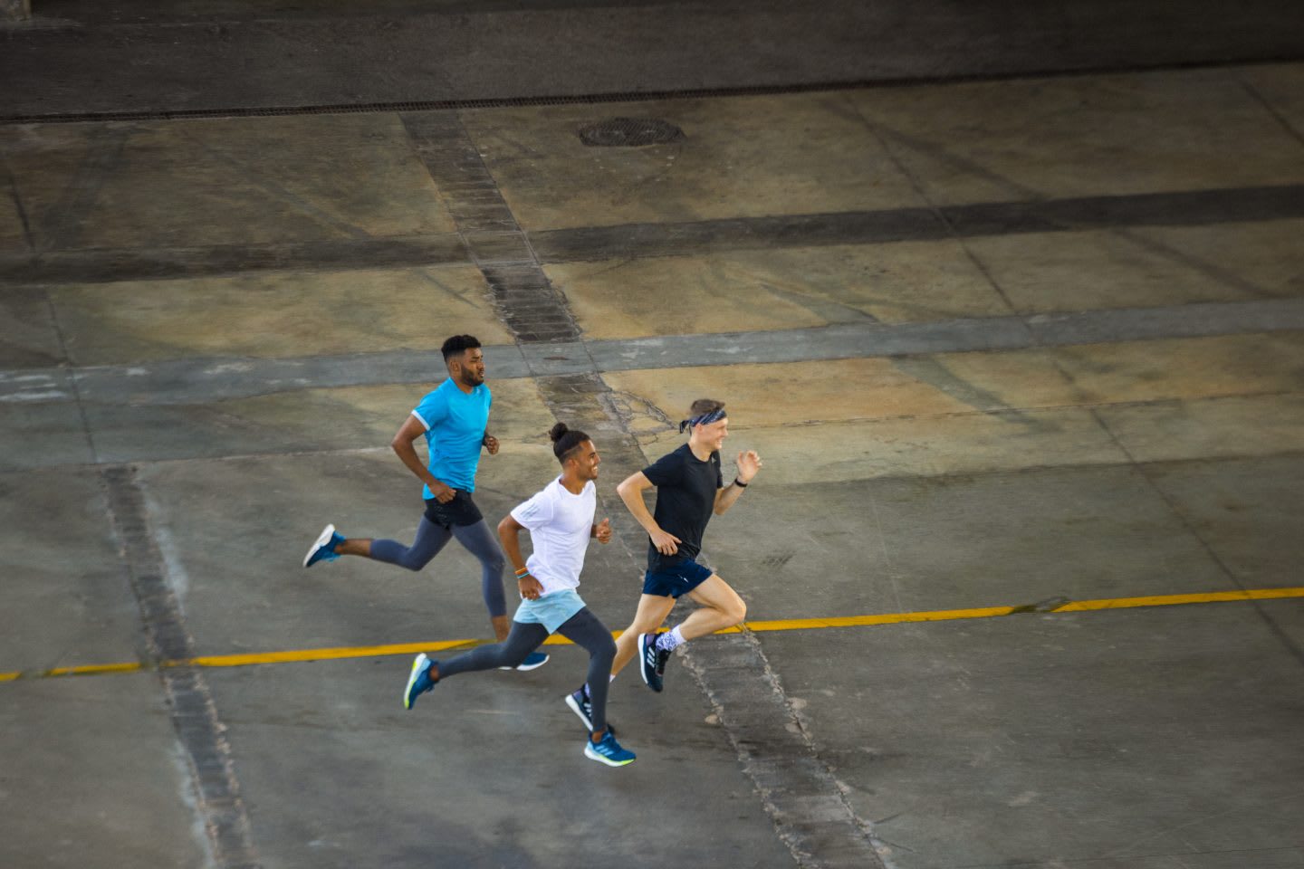 Three men running beside each other on concrete ground, teamwork. teammates, diversity, sports, GamePlan A