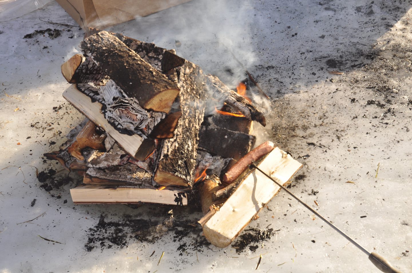 Wood fire on ice with hotdog cooking, roasting, warmth, heat