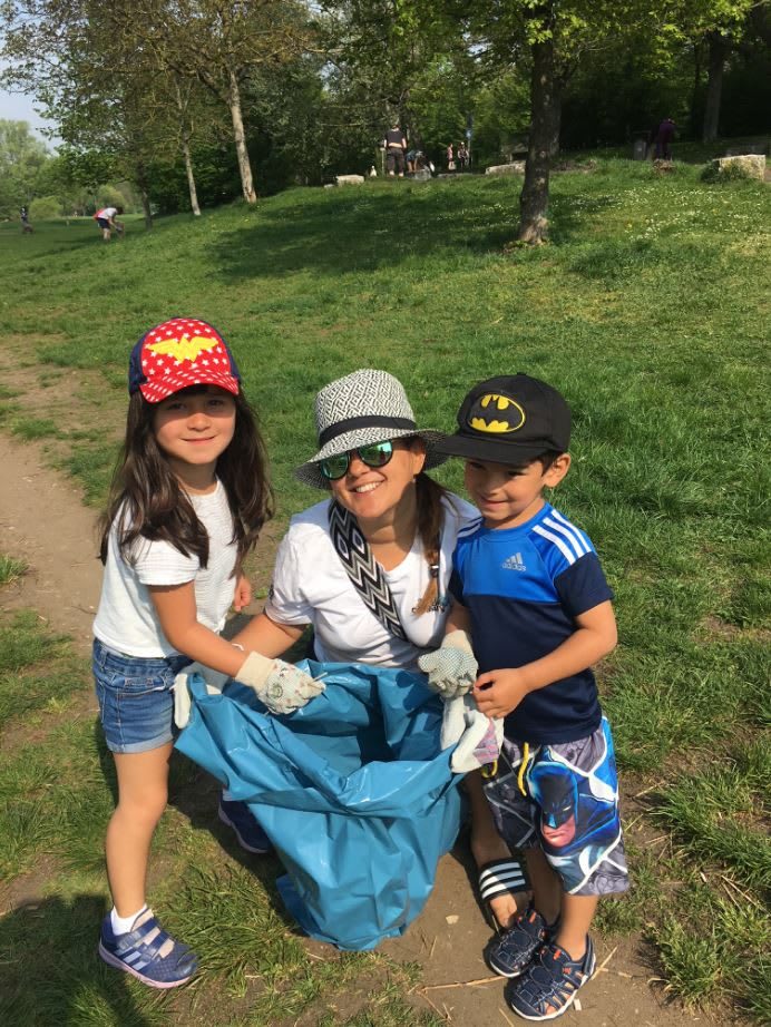 A mum and her son and daughter standing next to each other and smiling. They hold a plastic bag full of trash in their hands. collecting trash, nature clean-up, sustainability, family, GamePlan A