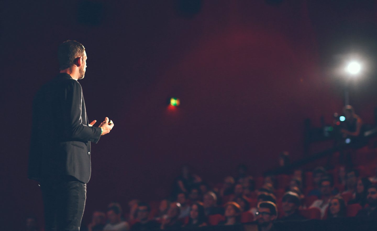 Florian Bernard presenting on stage in front of an audience in a dark room with the spotlight on him. pitching, performance, public speaking, audience, GamePlan A