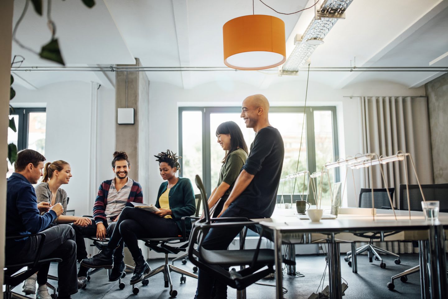 A team of young people is discussing something at a meeting held in a bright, creative office space. team members, meeting, group discussion, collaboration, GamePlan A