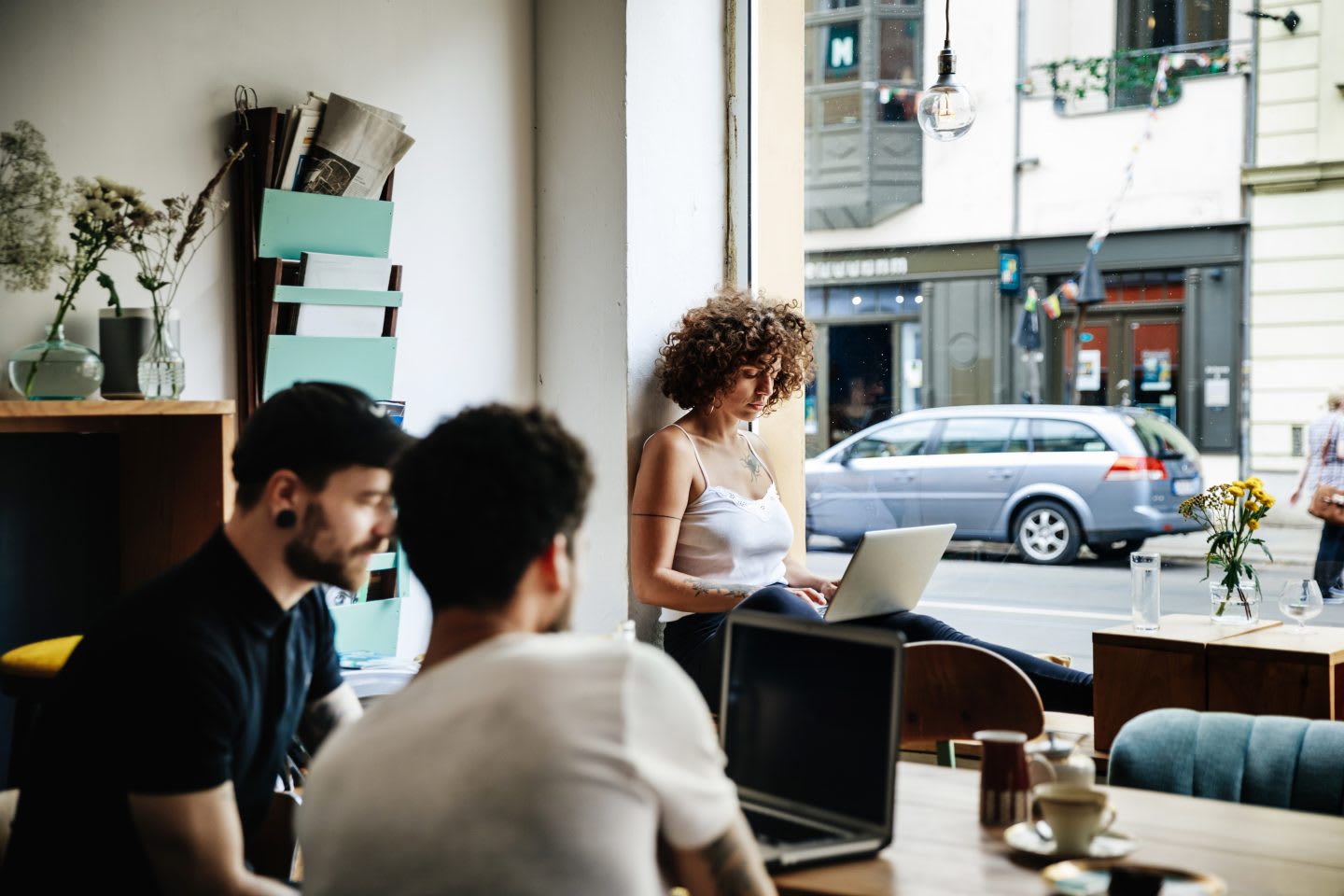 A young woman and two men working separately on their laptops at a cafe. quiet, concentration, work environment, flow state, GamePlan A