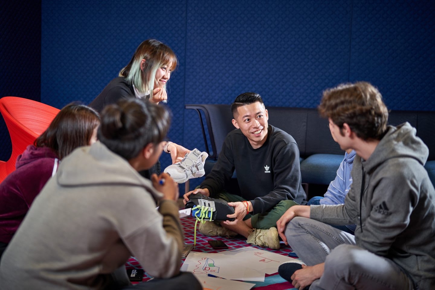 Group of designers sitting on the floor evaluating new shoe designs and giving each other feedback