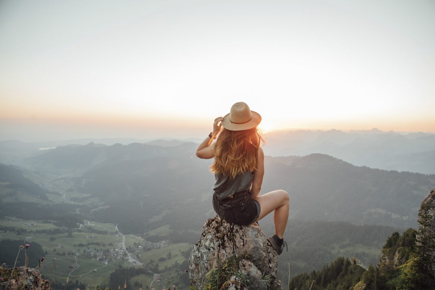 Woman sitting on a rock looking at the landscape in front of her. habits and routines, improving productivity, healthy lifestyle, rest and recovery, GamePlan A