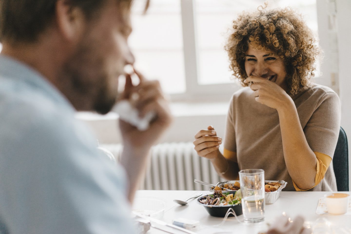 A man and woman sitting together and laughing together while they eat. habits and routines, improving productivity, healthy lifestyle, rest and recovery, GamePlan A