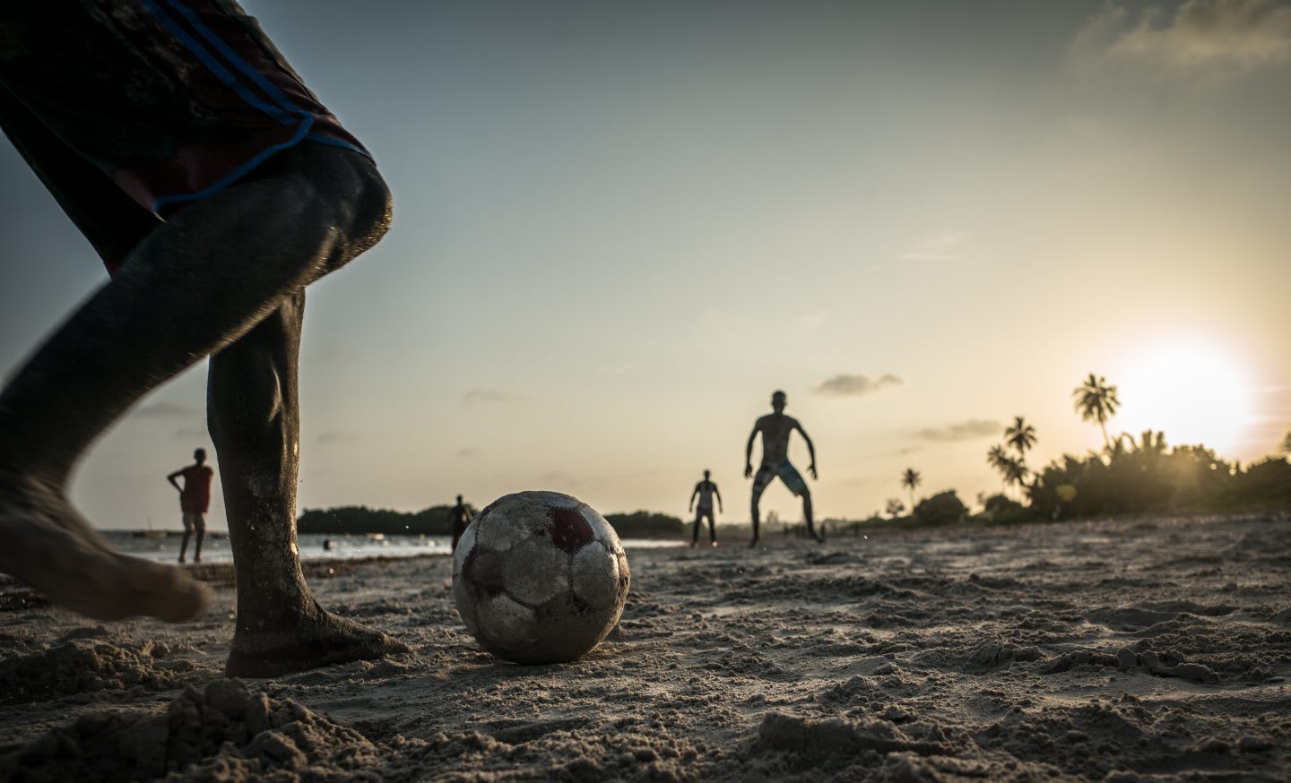 men playing football on a beach, volunteering
