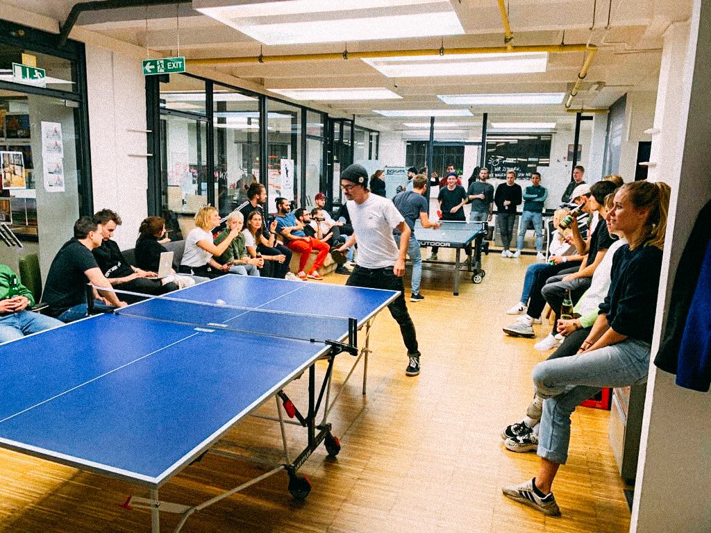 Group of people sitting in a room, some are playing table tennis. How to build a creative workplace culture, JvM, workplace, collaboration, creativity, team-building, GamePlan A