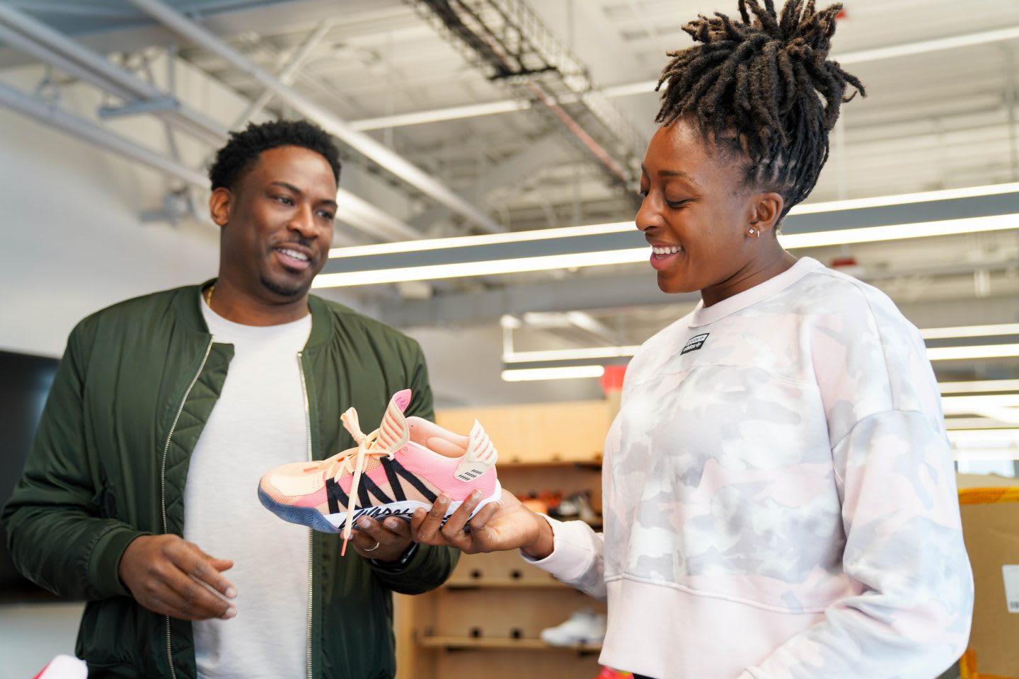 WNBA player Nneka Ogwumike holding sneaker and talking to colleague in the office, creativity, sports, work, collaboration, teamwork, teammates, GamePlan A