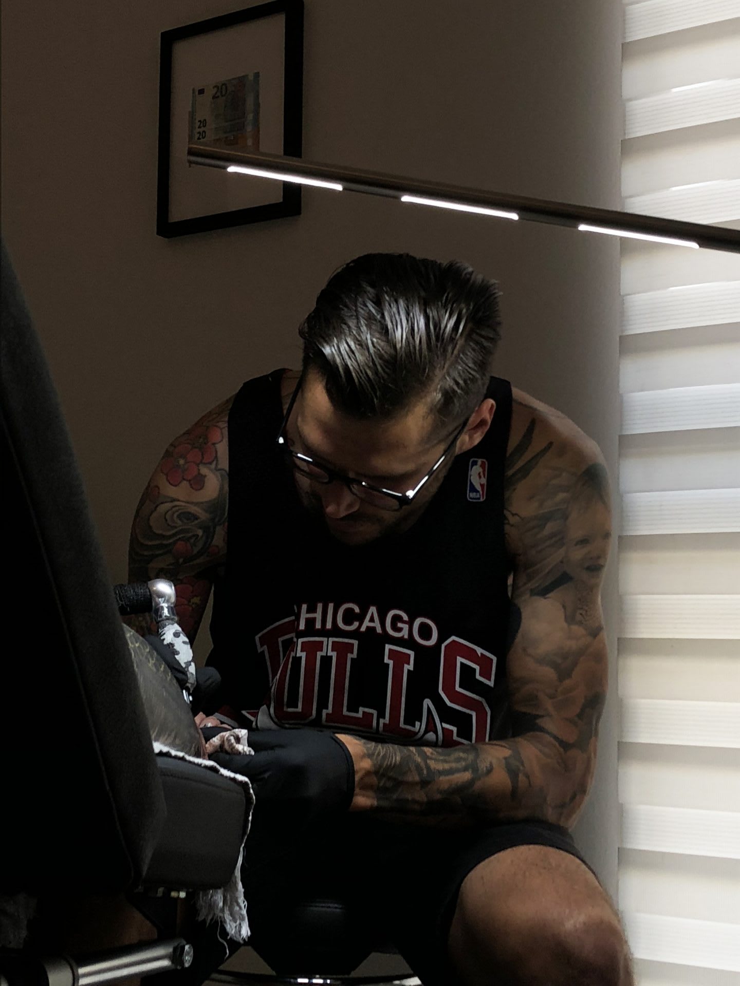 A man in a tank top tattooing someone.