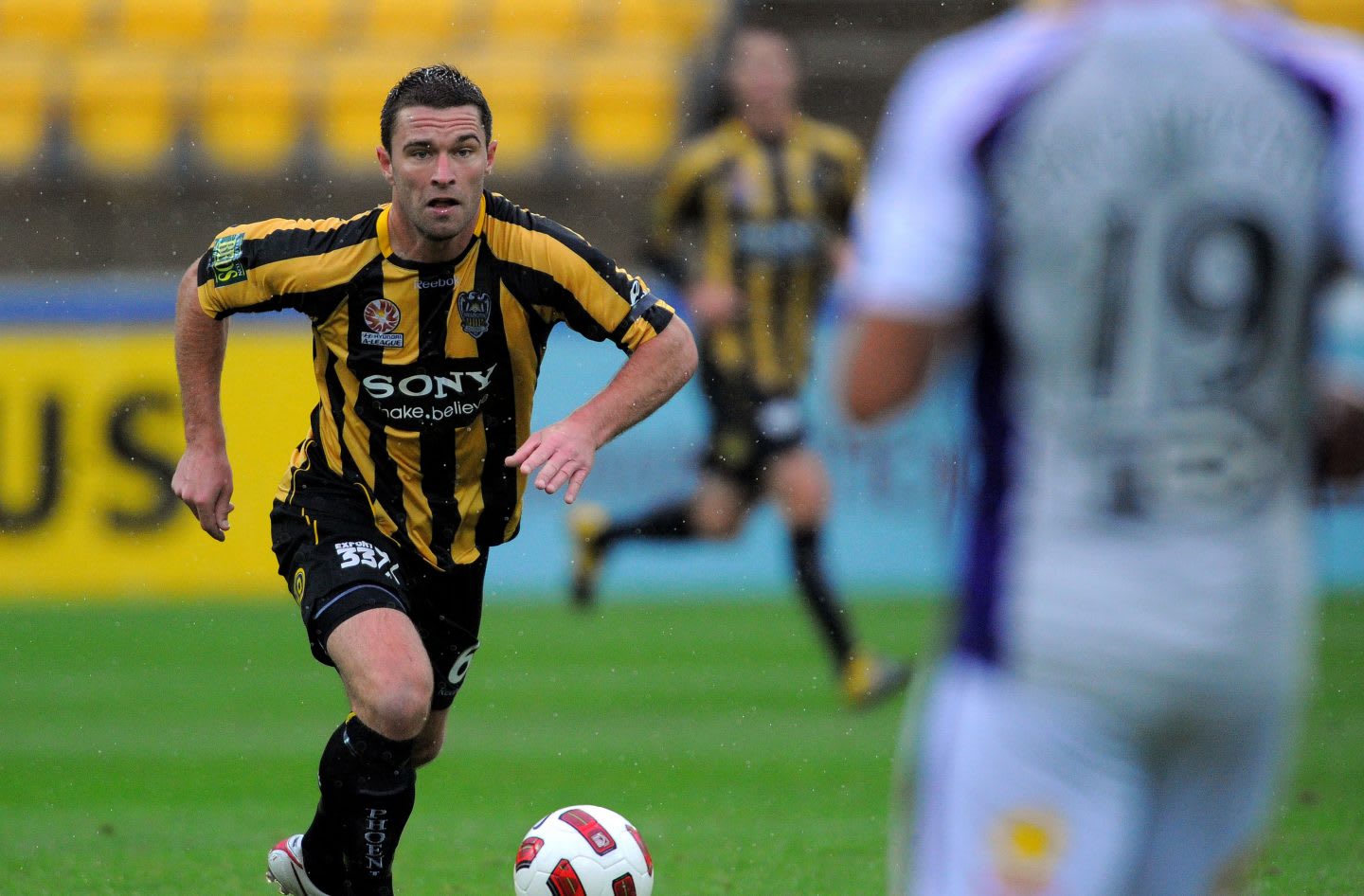 Allbirds co-CEO Tim Brown running towards the ball during a football game in New Zealand, sports, exercise, fitness, football, soccer, team