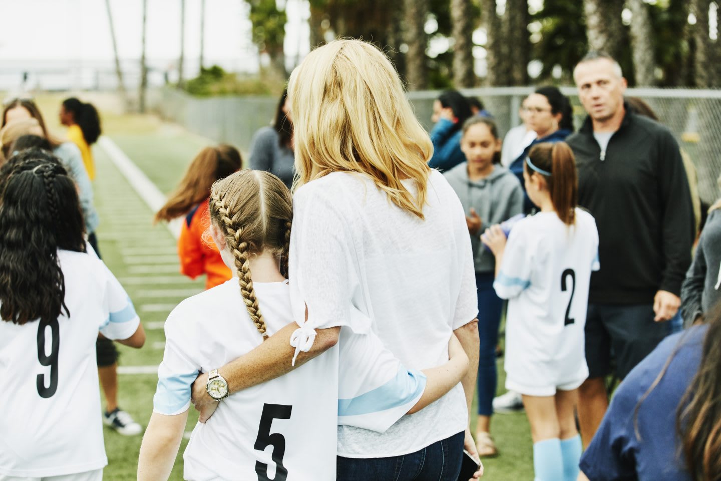 Mother embracing young female soccer player on sidelines after game. Purpose, purpose driven life, joy, GamePlanA.