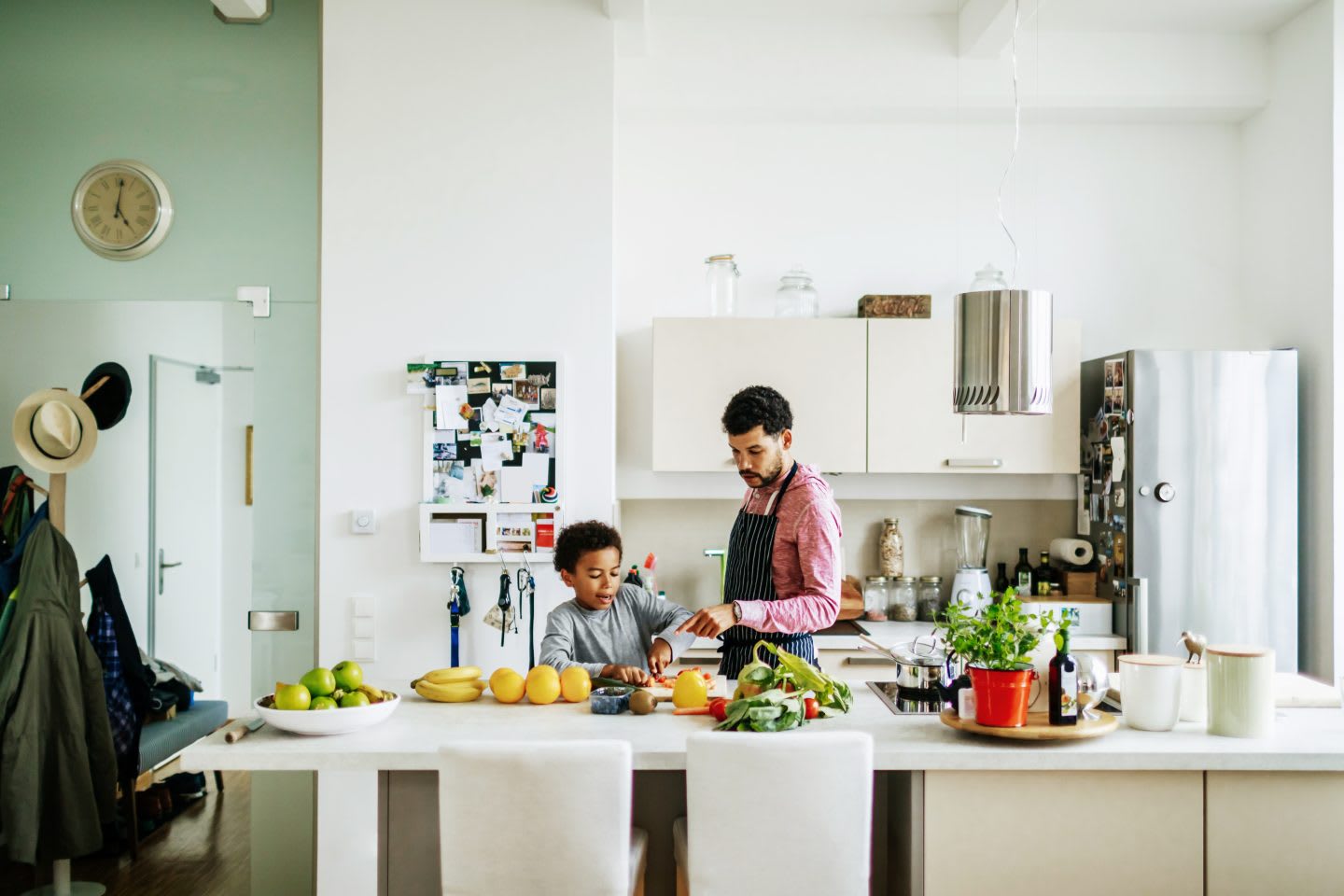 A father and son at home in the kitchen helping each other prepare some lunch.
