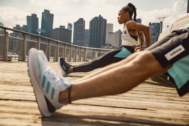 A women and a man stretching on a bridge in front of a city skyline. Mindset, Athlete, Exos, Positive Mindset, GemePlanA.