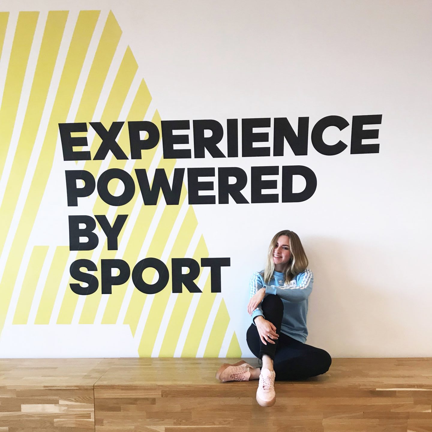 Woman sitting in front of a sign on the wall, adidas, employee, office, culture, sport