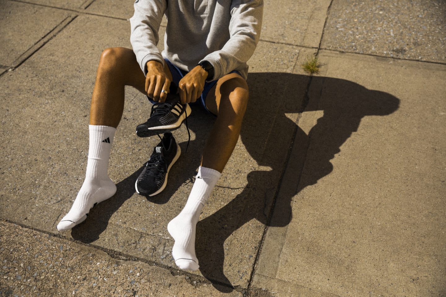 Person sitting on the ground lacing up running shoes before running, workout, active, fitness, exercise, adidas
