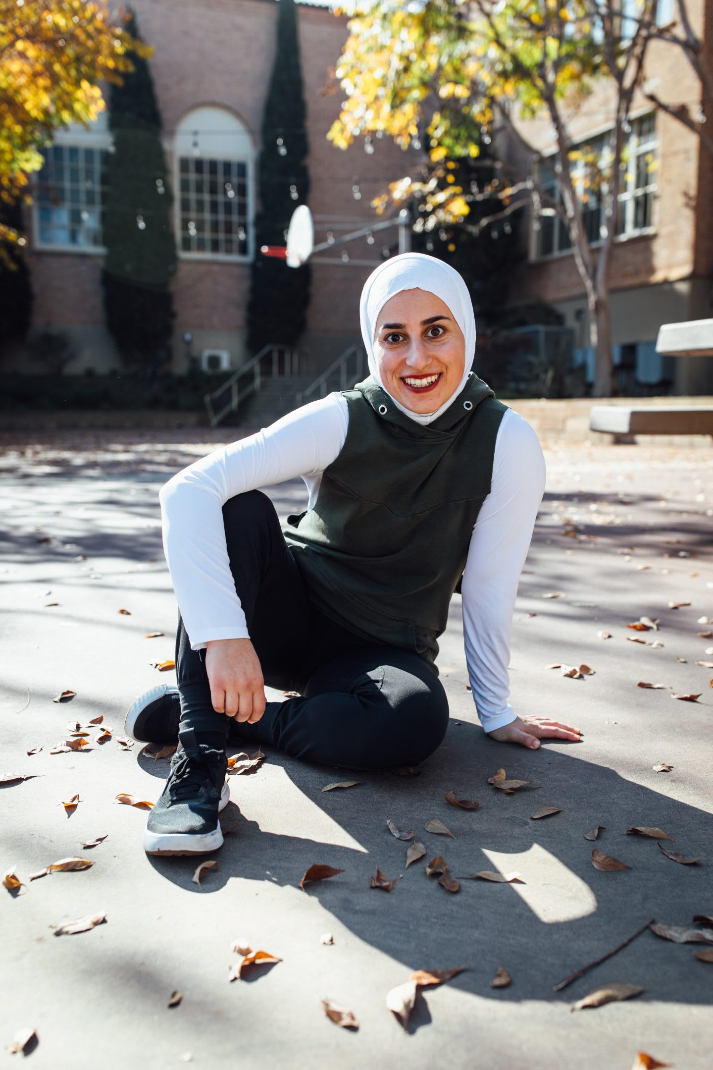 Girl sitting on the ground smiling, parkour, athlete, sports, action, fitness, Sara Mudallal