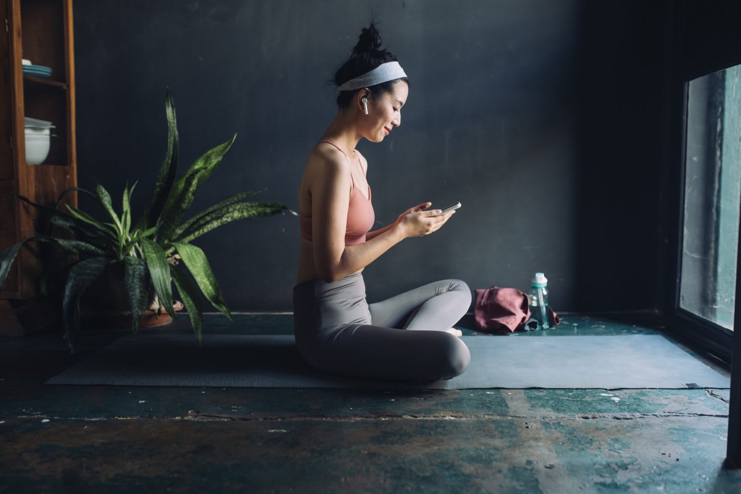 Young Asian woman with earphones sets up a music playlist before exercising, fitness, workout, music, yoga, sport, girl