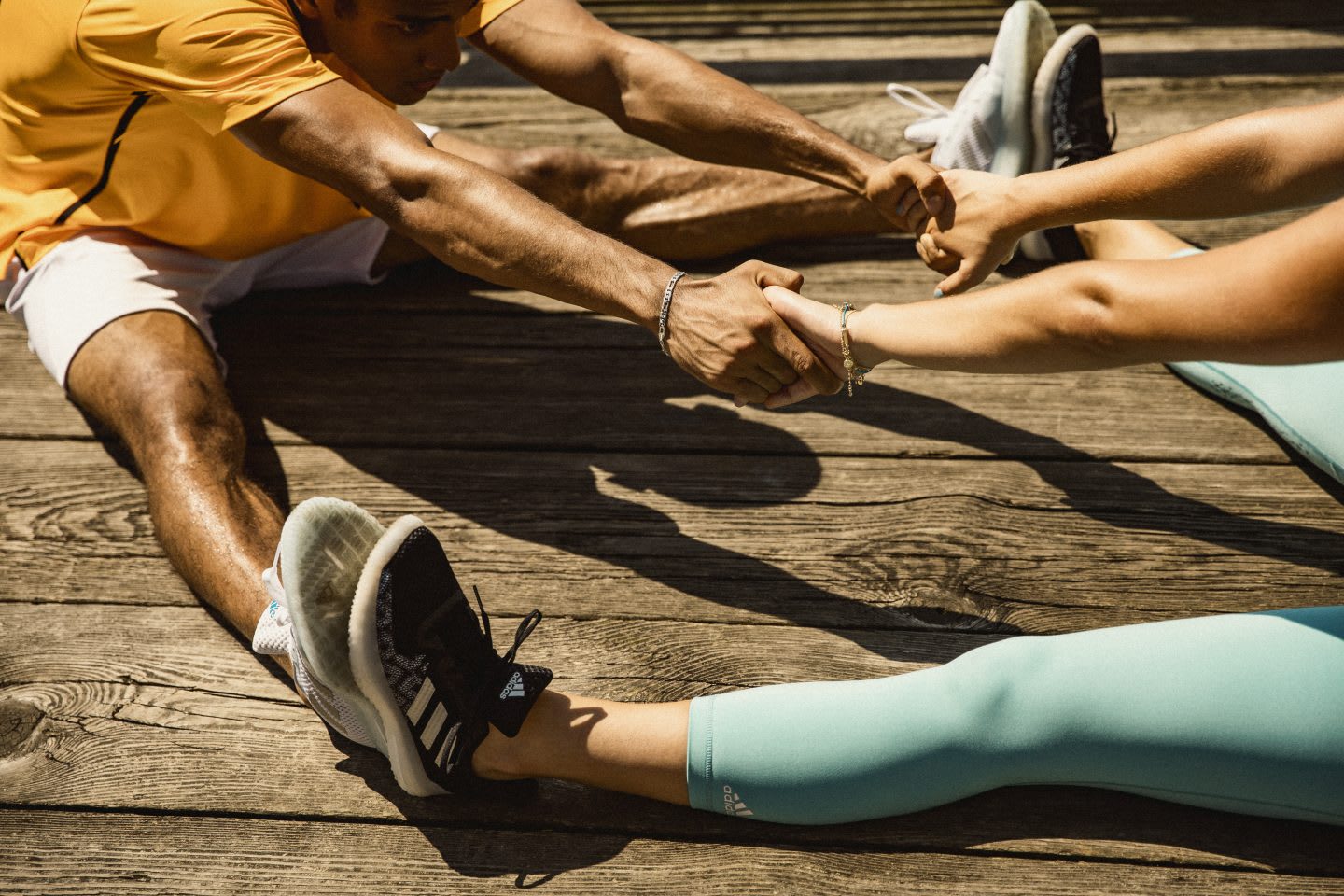 Two people holding hands and stretching after exercising, workout, sport, sport attire, adidas, warmup