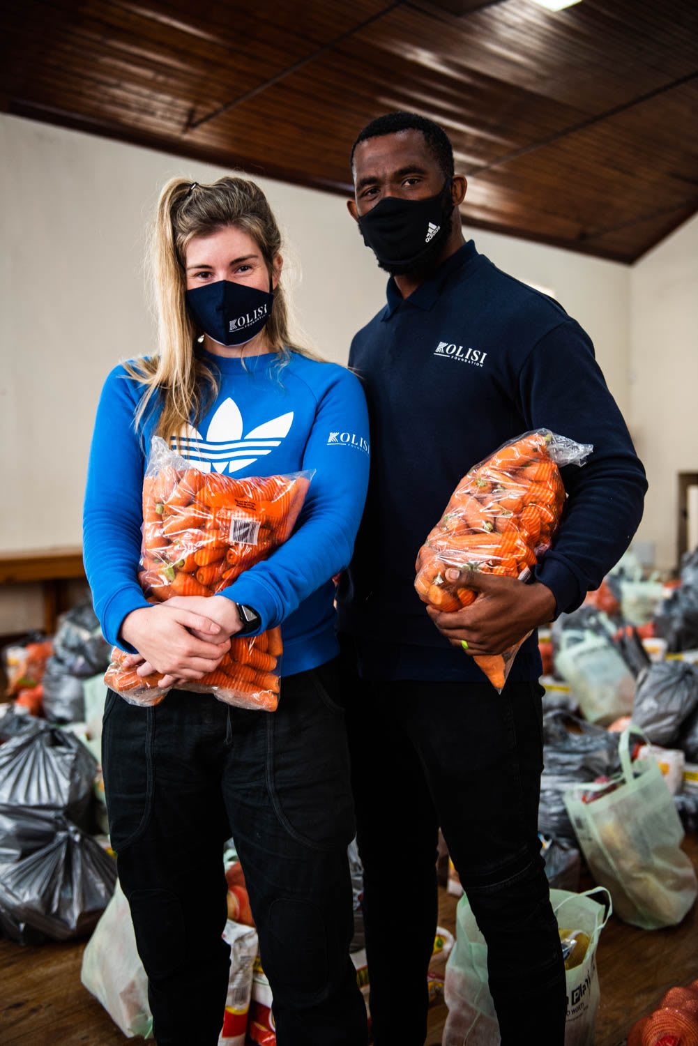Rachel and Siya Kolisi holding bags of carrots for communities in South Africa during coronarvirus pandemic, volunteering, donation, help. South Africa, Kolisi Foundation