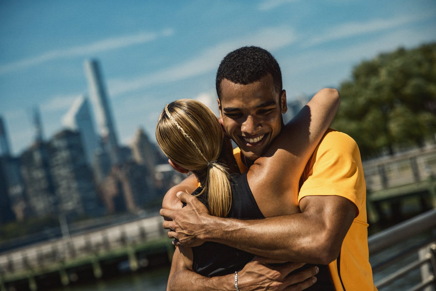 Man wearing yellow t-shirt smiling while hugging a blonde woman, teamwork. support, friendship, happiness, sports, sportsmanship, adidas