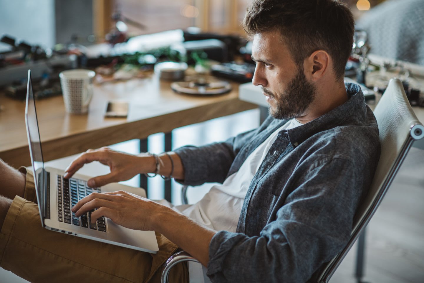 Man in home business workshop. Working table full of different tools and items needed for repairing electrical circuits, remote working, laptop, home office