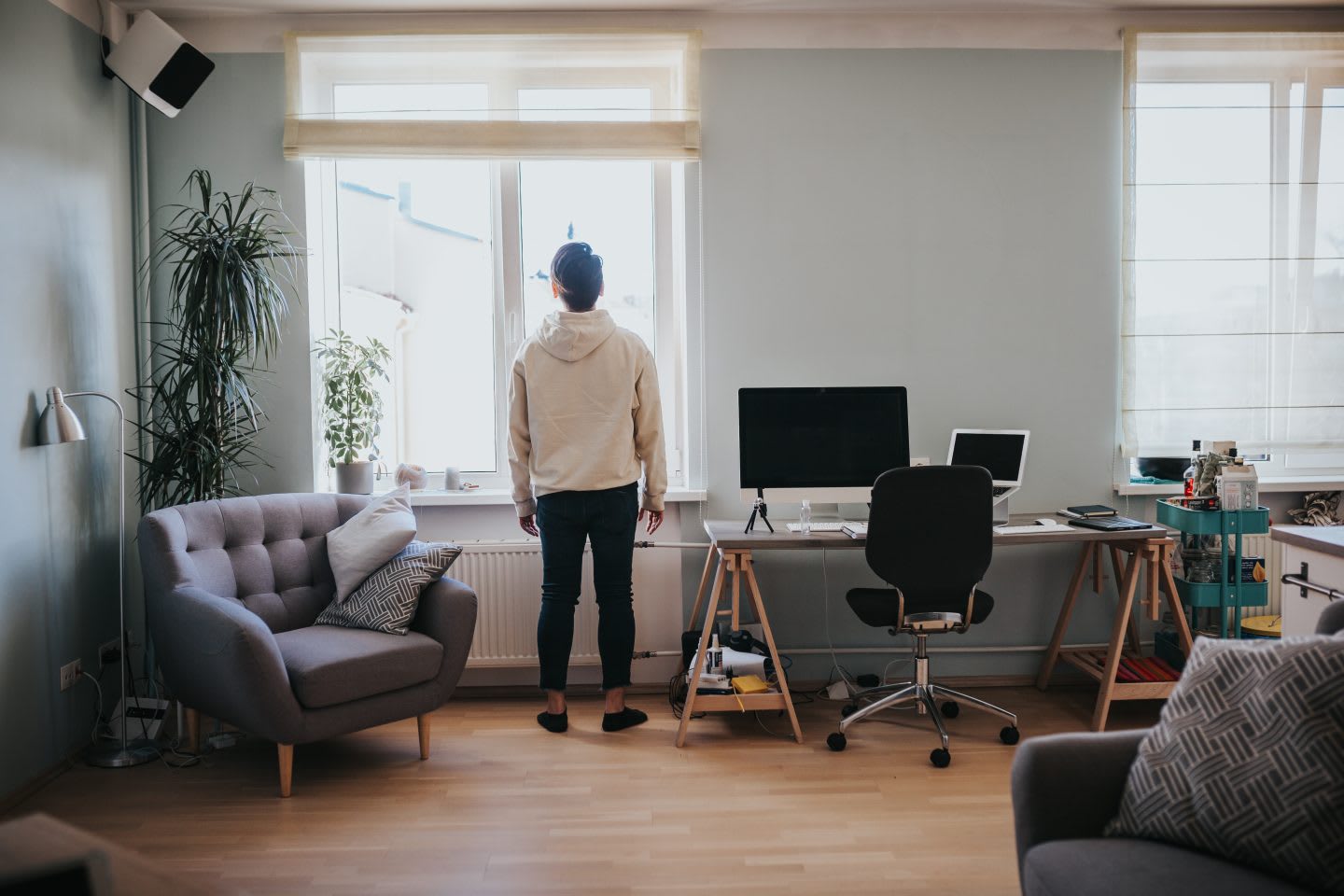 Man in white sweater staring out of window while working from home, stress, isolation, fatigue, lockdown, home