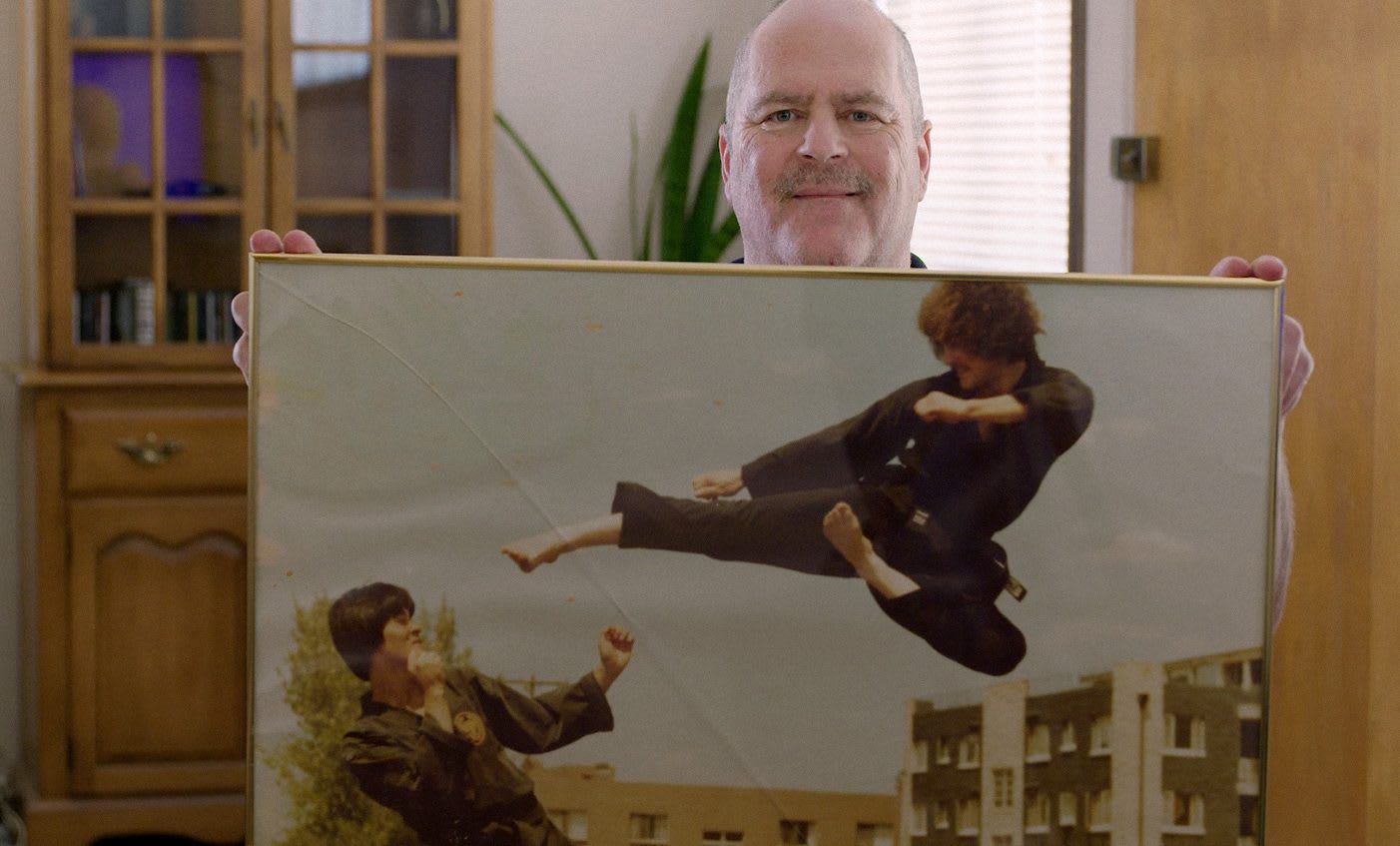 Man holding up an old picture of his younger self in a karate dual, sport, memory, fitness, EXOS