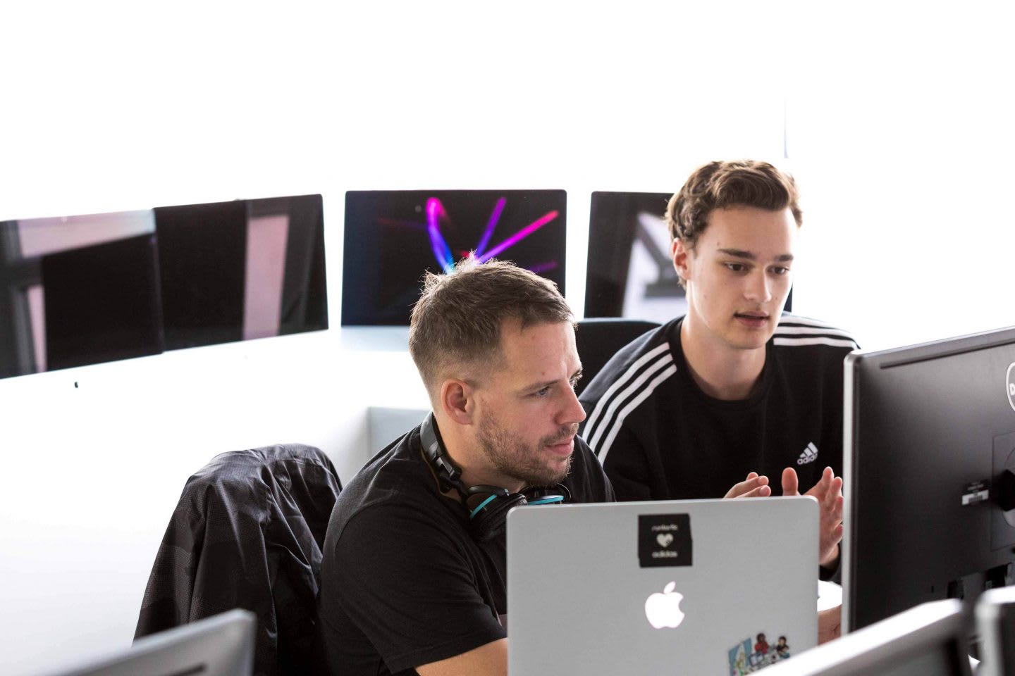 Two men working behind computer and laptop screens in an office, collaboration, teamwork, colleagues, employees, Runtastic. Linz, Austria