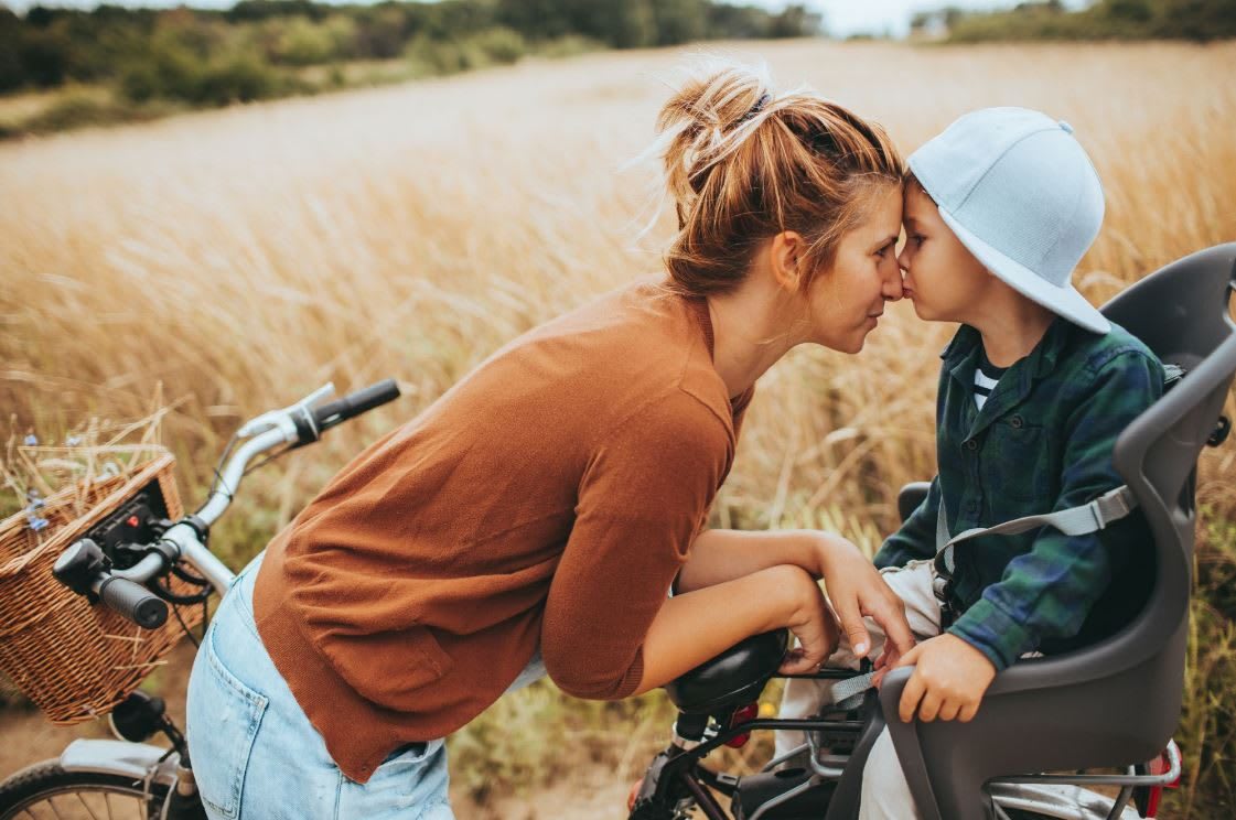Blonde woman kissing her child on the face while on a bike, outdoor, activity, family, motherhood, kids, child